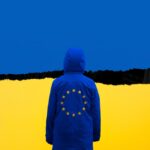 a man in a blue jacket standing in front of a yellow and blue wall