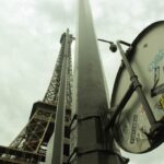 a street sign with stickers on it in front of the eiffel tower