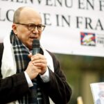 a man speaking into a microphone in front of a sign