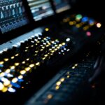 A close up of a computer keyboard and two monitors