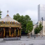 A carousel in the middle of a square with a building in the background
