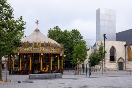 A carousel in the middle of a square with a building in the background