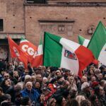 A large group of people holding flags in front of a building