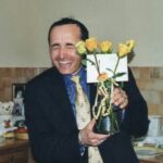 Man happily shows off a bouquet of yellow roses.