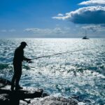 A fisherman is fishing by the sea.