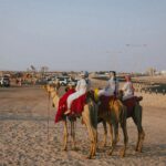 People riding camels in a desert landscape
