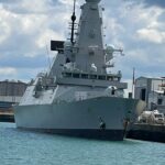 A large gray warship docked in the harbor.