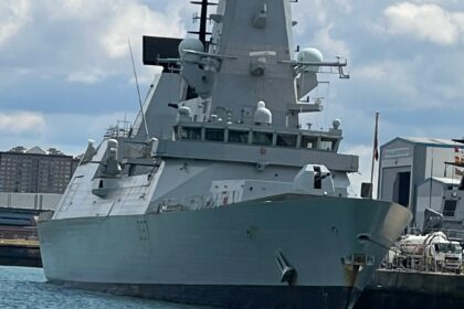 A large gray warship docked in the harbor.