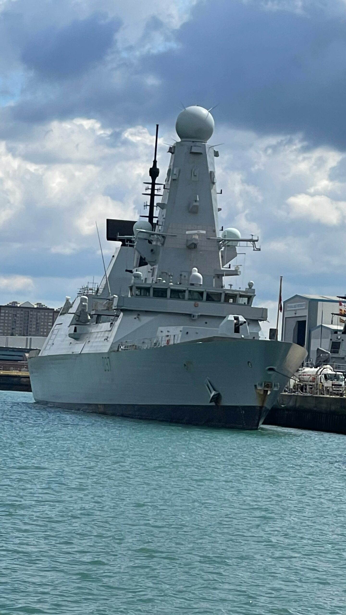 A large gray warship docked in the harbor.