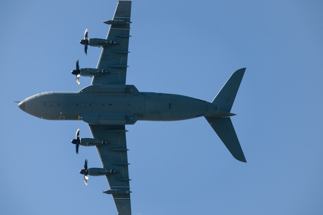 Four-engine turboprop aircraft flying in clear blue sky.