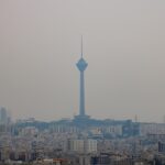 A tall tower stands over a hazy city skyline.