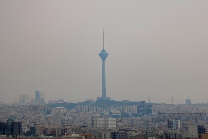 A tall tower stands over a hazy city skyline.