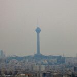 A tall tower stands over a hazy city skyline.