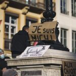 man in black coat standing beside brown and white concrete building during daytime