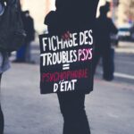 a woman holding a sign on the side of the road