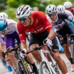 A group of men riding bikes down a road