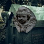 A statue of a little girl with angel wings on a grave