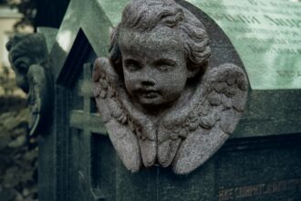 A statue of a little girl with angel wings on a grave