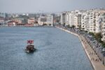 A boat sails near a coastal city's waterfront.