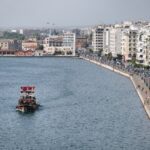 A boat sails near a coastal city's waterfront.