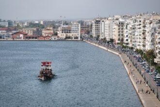 A boat sails near a coastal city's waterfront.