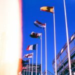 Several national flags flying against a blue sky.
