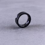 A black ring with white speckles on a gray surface