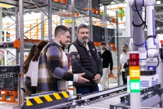 Men observe automated conveyor belt system in warehouse
