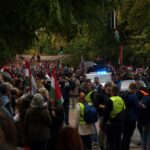 Crowd of people waving hungarian flags near police car