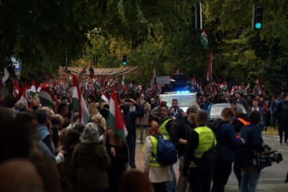 Crowd of people waving hungarian flags near police car