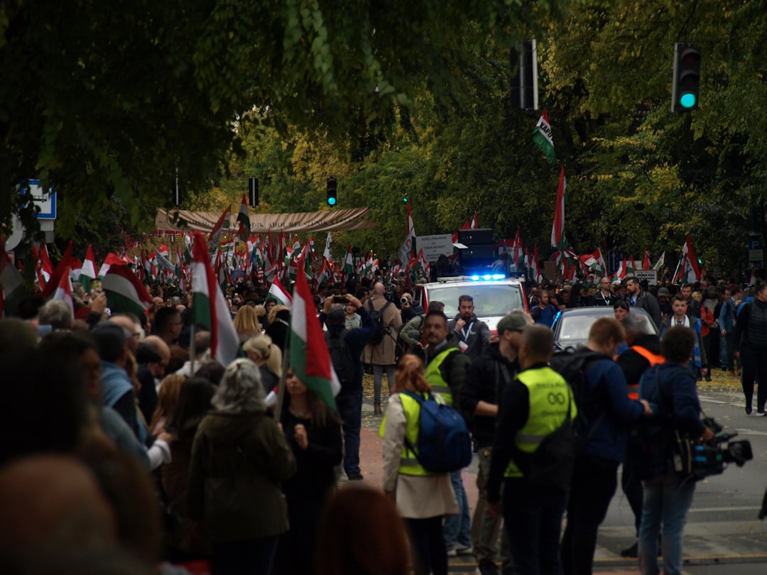 Crowd of people waving hungarian flags near police car