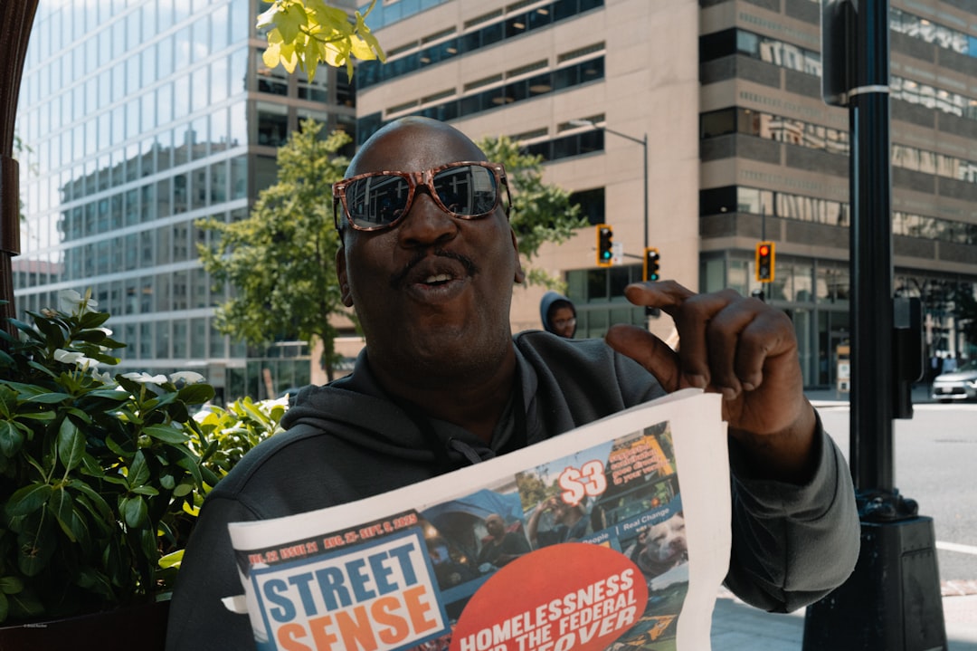 Man holds up "street sense" newspaper on city street.