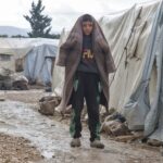 Young boy wrapped in blanket in refugee camp