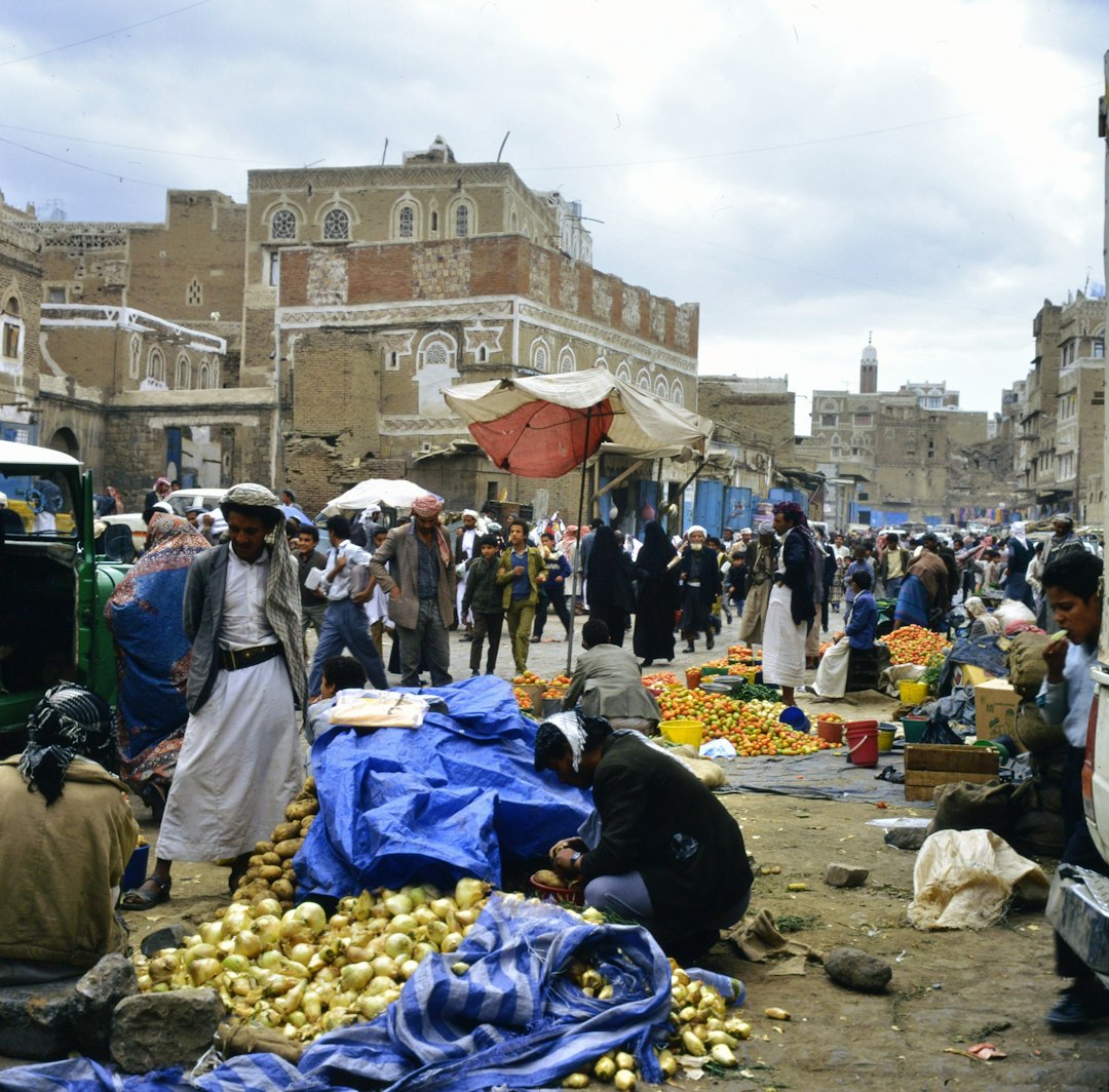 Bustling marketplace with people and goods in a historic city.