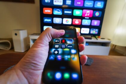 Hand holding smartphone controlling smart TV apps