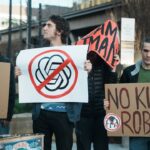 Protesters hold signs against ai and killer robots.
