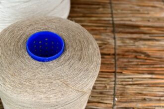 Two spools of thread on a textured surface.