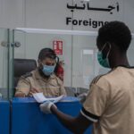 a man wearing a face mask and gloves standing in front of a counter