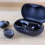 a pair of black ear buds sitting on top of a wooden table