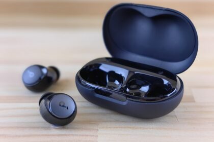 a pair of black ear buds sitting on top of a wooden table