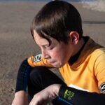 A young boy sitting on top of a surfboard