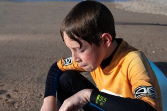 A young boy sitting on top of a surfboard