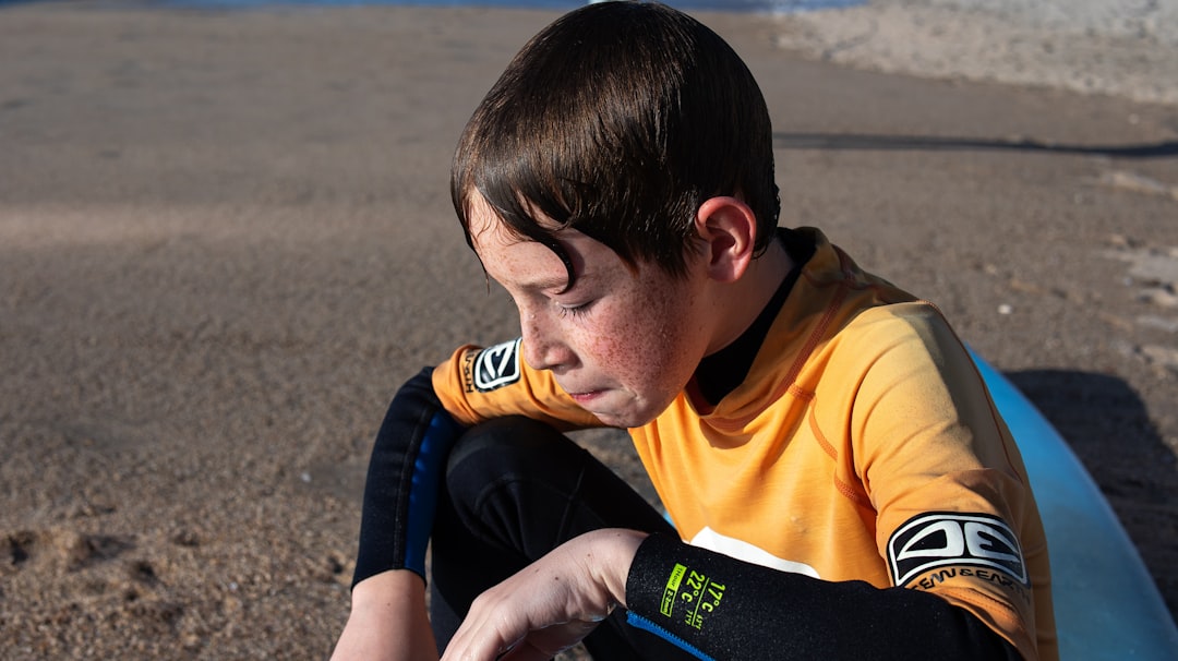 A young boy sitting on top of a surfboard