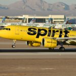 A yellow spirit airplane on the runway of an airport