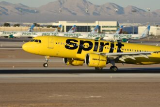 A yellow spirit airplane on the runway of an airport
