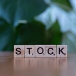 A wooden block spelling the word stock on a table