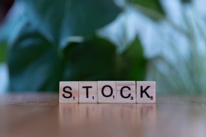 A wooden block spelling the word stock on a table