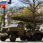 A russian military vehicle parades in the street.