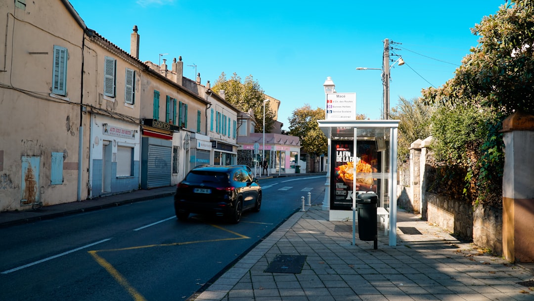 Car driving down a street with buildings and bus stop.