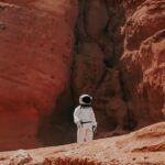 photography of astronaut standing beside rock formation during daytime